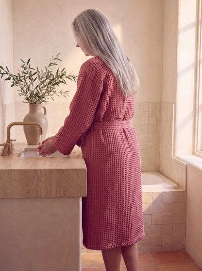 Femme de dos portant le peignoir Lumä en nid d’abeille bois de rose devant un lavabo