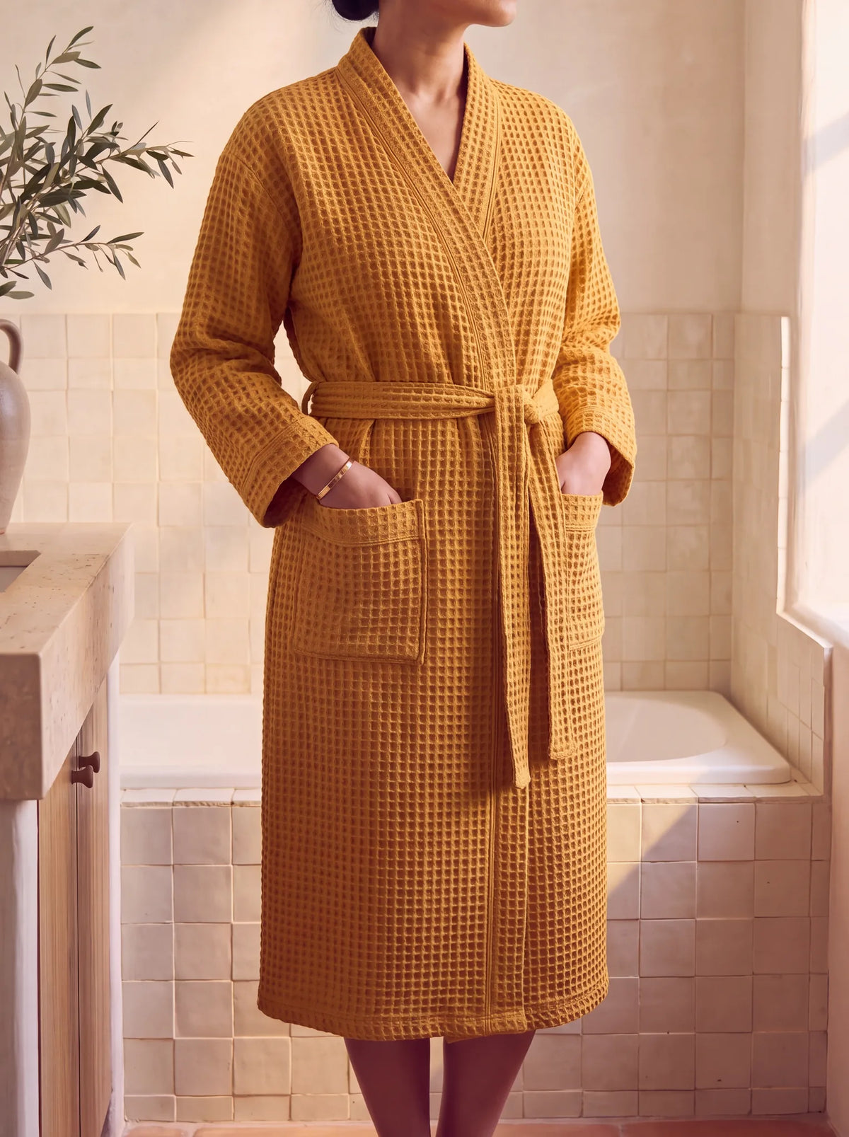 Peignoir Lumä en coton nid d’abeille jaune porté par une femme, mains dans les poches